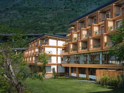 A modern resort hotel with a wooden exterior featuring balconies and glass windows.