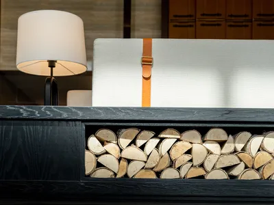 A black chest with a wooden storage compartment, featuring a lamp and a white cushion.
