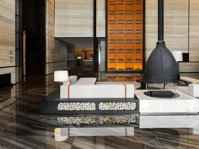 Modern hotel lobby featuring wood accents, stone flooring, and metal elements