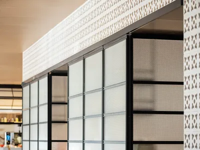 Modern restaurant interior with glass partitions, contemporary furniture, and concrete accents.