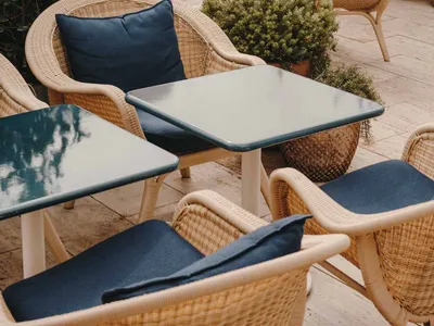 Outdoor seating area of a cafe with wicker chairs and blue cushions.