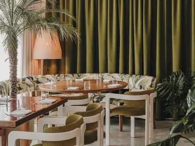 A modern restaurant interior with green globes and tropical plants.