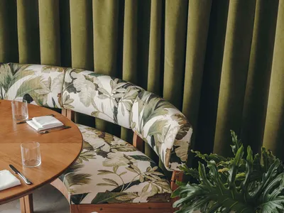 Modern restaurant interior with terrazzo tiles and green curtains.