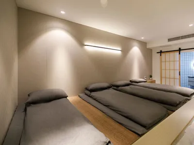 A minimalist bedroom with grey beds and wooden accents.