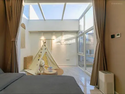 A modern bedroom featuring a comfortable bed, a playful children's tent on the floor, and a spacious window area with a view