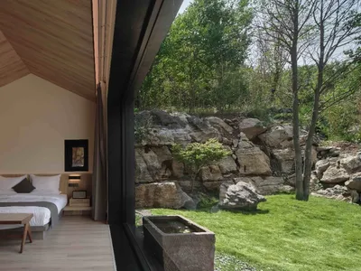 Minimalist bedroom with wooden elements and a view of natural surroundings.