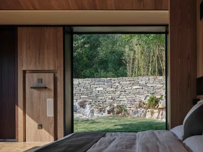 Minimalist bedroom featuring wood, stone, and concrete materials.