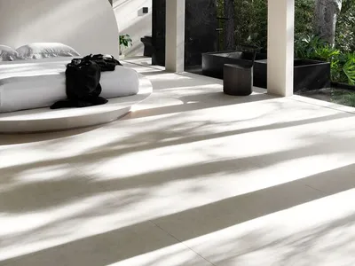 Modern minimalist bedroom featuring concrete flooring with natural light streaming in from a garden view.