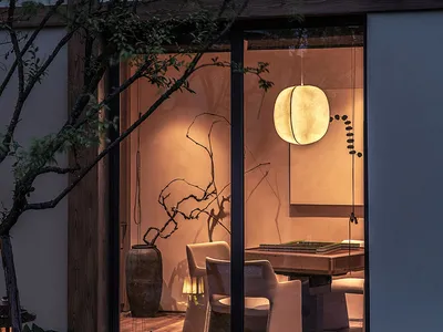 A serene evening scene showcasing a living room with soft, warm lighting, wooden furniture, and plant life.