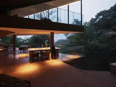 Modern restaurant with glass balcony overlooking lush forest.