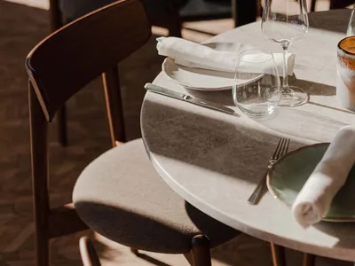 Modern restaurant table setting with white tiles, fabric upholstered chairs, white tableware, and minimalistic design element