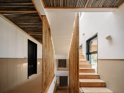 Modern staircase with bamboo railings and wooden steps in a well-lit interior space.