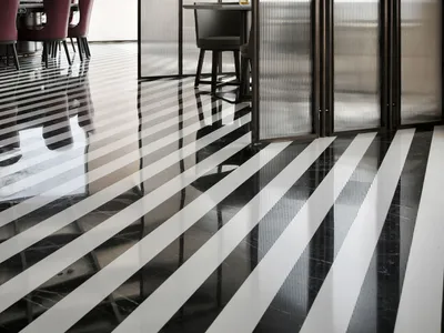 A modern restaurant interior with black and white striped flooring and glass walls.