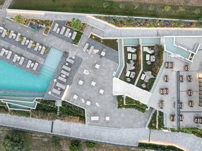 Luxury hotel resort with indoor and outdoor spaces, featuring a swimming pool, lounge chairs, and dining areas.