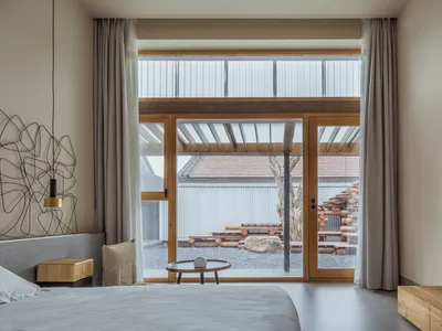 Minimalist bedroom featuring concrete floor, wooden bed frame, and glass windows