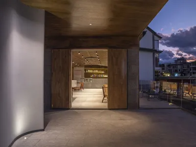 Modern restaurant bar with wooden panels, concrete floor, and metal accents.