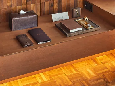 A modern hotel reception desk with wooden elements and a tray of notepads and cards.