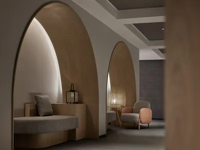 A modern minimalist hotel treatment room with wooden accents and cozy seating arrangements.