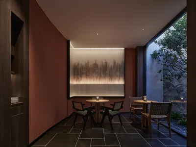 Circular table with chairs in a modern restaurant setting with a water feature and outdoor garden view.