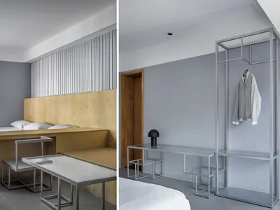 A minimalist bedroom with a metal structure, featuring a bed, desk, and integrated cabinets.