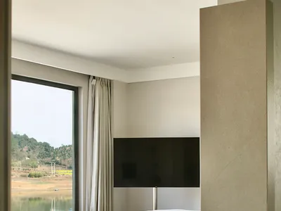 A minimalist bedroom with white bedding, concrete flooring, and a sleek glass and metal frame bed.