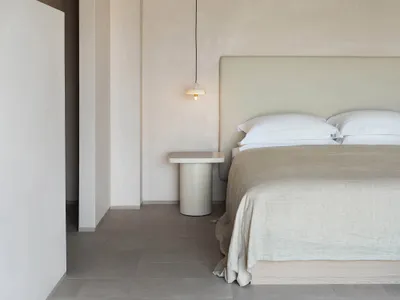 Minimalist bedroom with concrete sconce and concrete floor.
