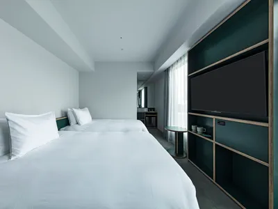 Minimalist hotel room featuring white bedsheets, dark wooden furniture, and glass windows.