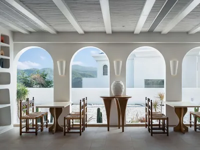 簡約風格的餐廳室內，擺設木質餐桌椅，開闊的窗戶可眺望山景。