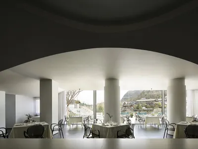 A sleek, modern restaurant interior with white stone flooring, white walls, and a minimalist design.