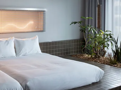 A minimalist bedroom with a bed and tile flooring.