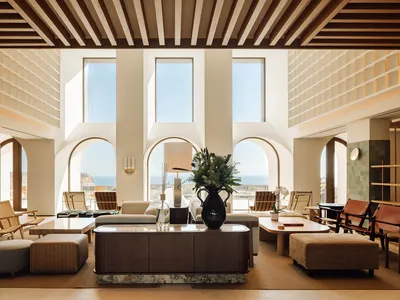 A modern hotel lobby featuring natural light through large windows and contemporary furniture.