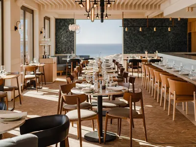 Modern restaurant interior featuring natural wood accents and an ocean view.