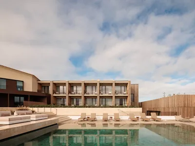 A luxurious hotel exterior with a swimming pool and relaxation area on the side.