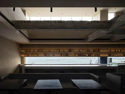 Industrial-style restaurant interior with wooden tables and a bar counter.