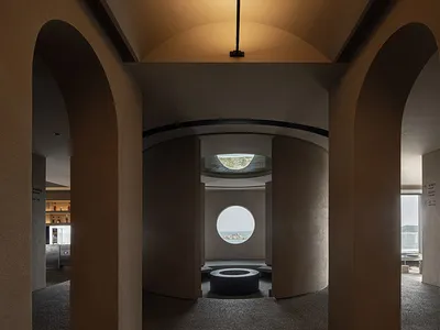 A minimalist restaurant interior with a concrete floor and circular windows.