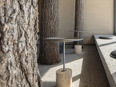 Modern cafe interior with tall concrete columns, minimalist furniture, and a naturalistic touch.