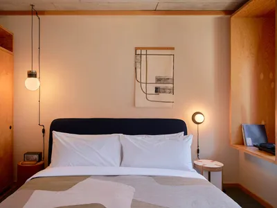 A minimalist bedroom featuring wooden walls, fabric bedding, and metal accents.