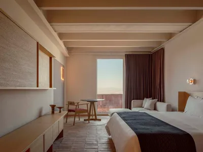 A minimalist bedroom featuring wooden furniture and textile accents.