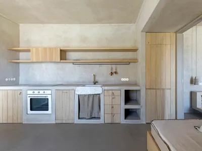 A minimalistic kitchen with concrete countertops and wooden shelves.