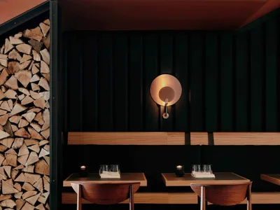 Modern restaurant booth made of wood with black walls and seating.