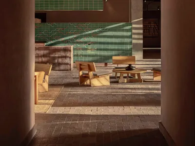Modern interior of a restaurant with green tile walls and wooden furniture.