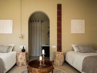 A minimalist bedroom with earth-toned bedding, wooden furniture, and decorative elements.