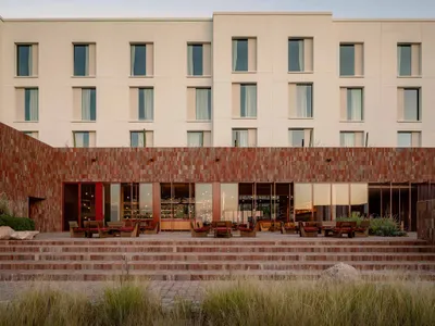 Modern hotel lobby featuring sandstone and wood materials, with a minimalist design approach.