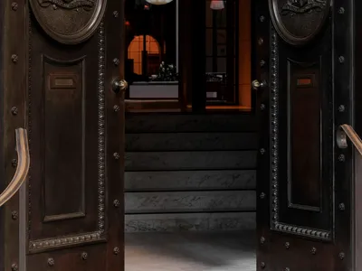 A luxurious hotel lobby with black metal doors adorned with leather and marble