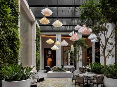 Modern restaurant interior with glass lampshades, concrete surfaces, and potted plants.
