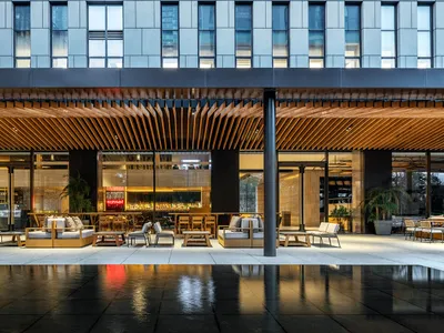 A modern restaurant interior featuring wooden tables and chairs, glass walls, and metal accents.