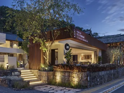Nighttime exterior of a modern cafe with a metal facade and stone pathway.