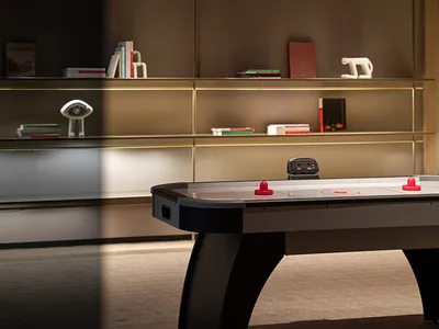 A modern industrial living room featuring metal bookshelves, a carpeted floor, and a wall-mounted shelf with books and decora