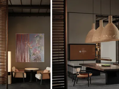 A minimalist hotel lobby features a wooden table, chairs, and a hanging rattan light fixture.