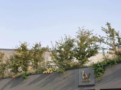 A modern hotel exterior with concrete walls and a green roof.